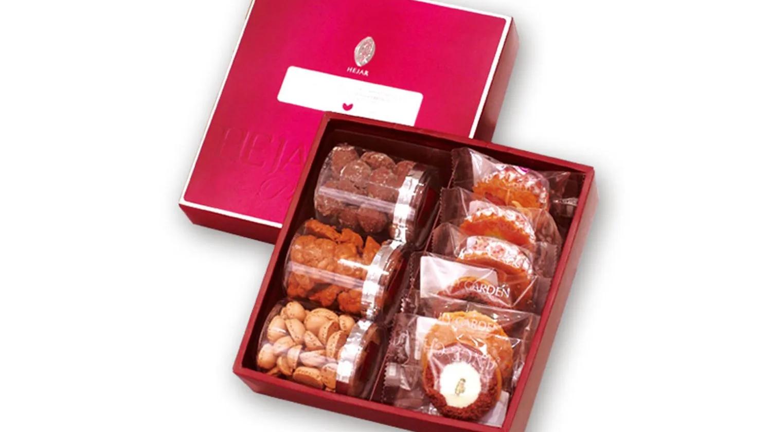 A red gift box containing an assortment of packaged snacks, including nuts and cookies, neatly arranged in compartments.