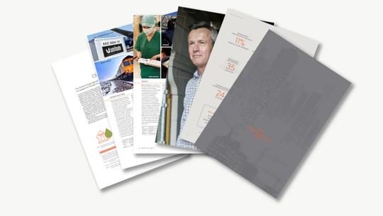 A stack of open magazines and brochures featuring various images and text, including a train, a healthcare worker, and a man in a checkered shirt.