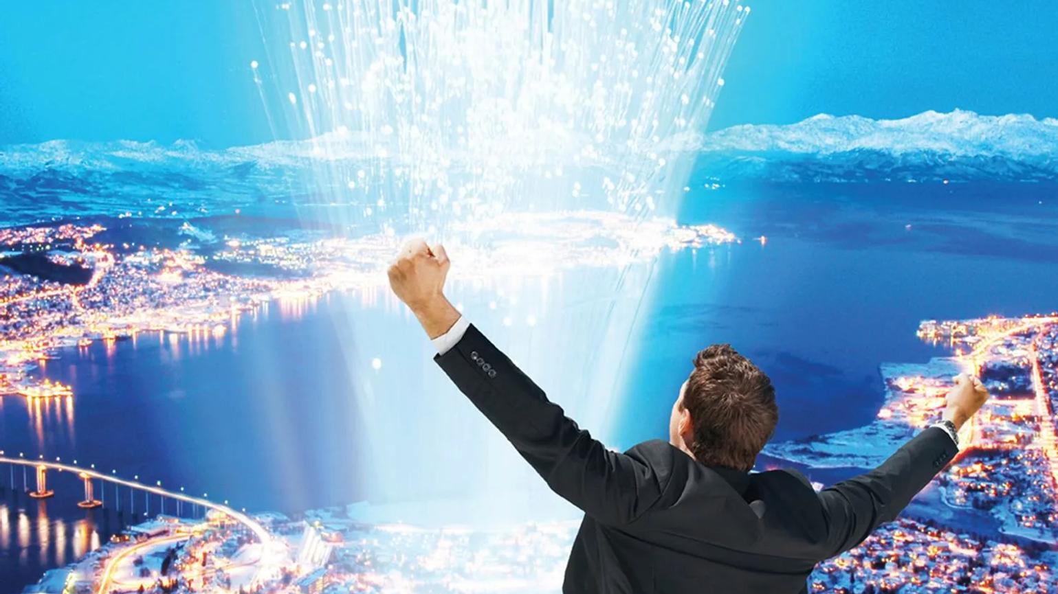 A person in a suit raising their arms triumphantly, overlooking a cityscape at night with illuminated buildings and roads, and a burst of light or data streams rising into the sky.