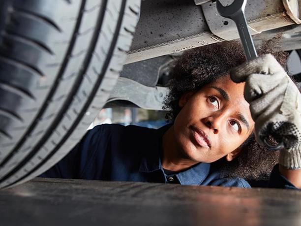 A mechanic wearing gloves is inspecting the underside of a vehicle.
