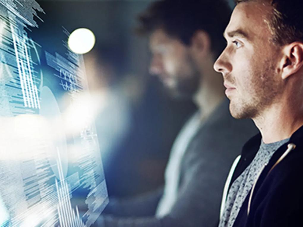 A man intently looking at a digital screen displaying data and graphs.