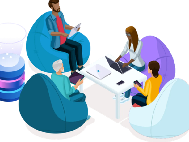 Four people sitting on bean bags around a small table, engaged in work with laptops and tablets.