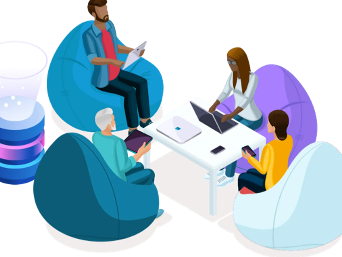 Four people sitting on bean bags around a small table, engaged in work with laptops and tablets.