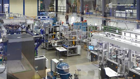 A large industrial facility with various machinery, workstations, and equipment, showcasing a complex manufacturing setup.
