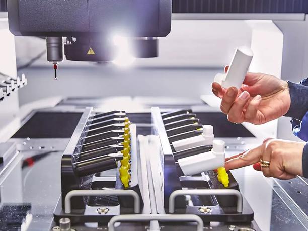 A person is handling a white cylindrical object in a manufacturing setting