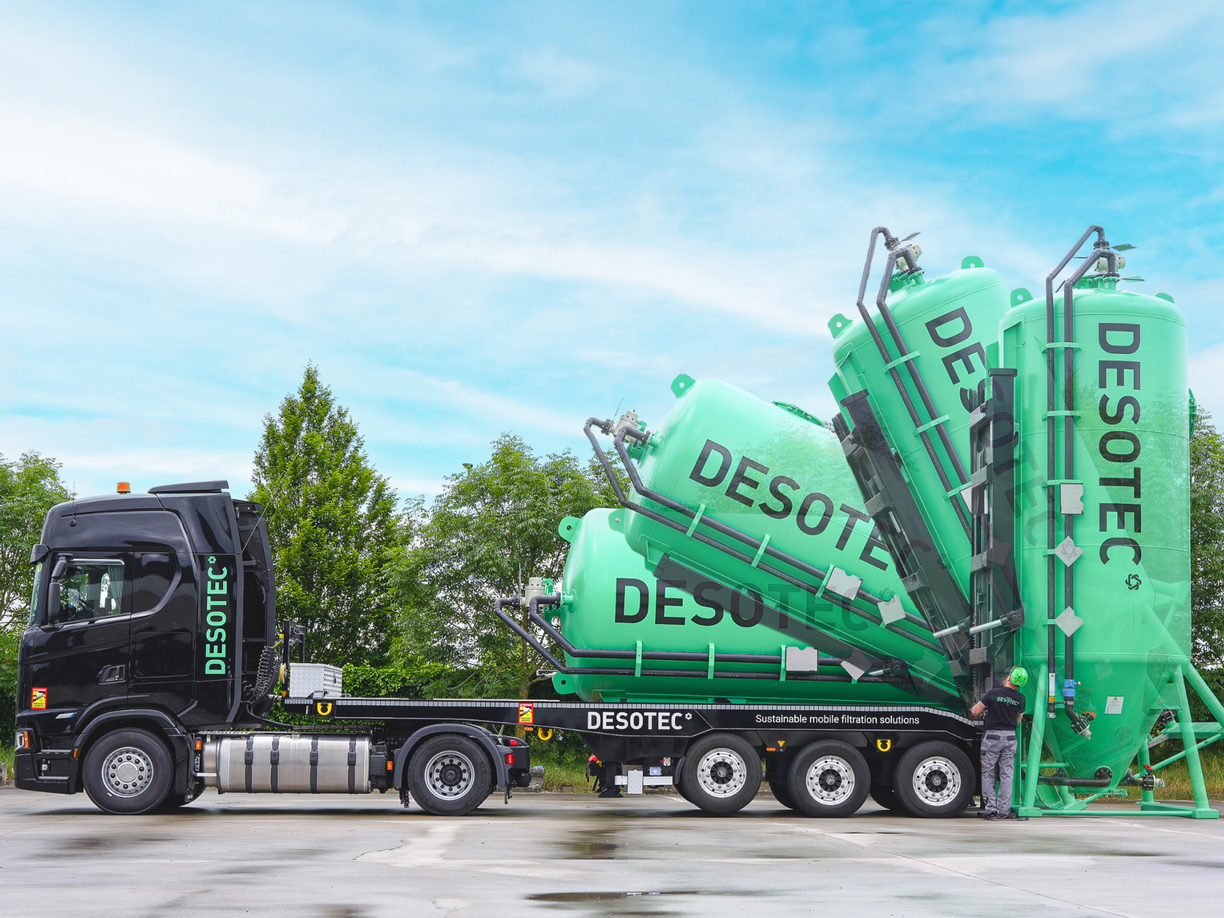 A truck with a tank thats being lift off with the DESOTEC logo on it.