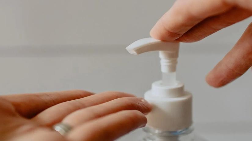 Close-up of a person pressing the pump of a hand sanitizer bottle.