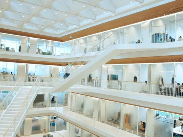 A modern, multi-level office interior with open walkways and glass-walled offices.