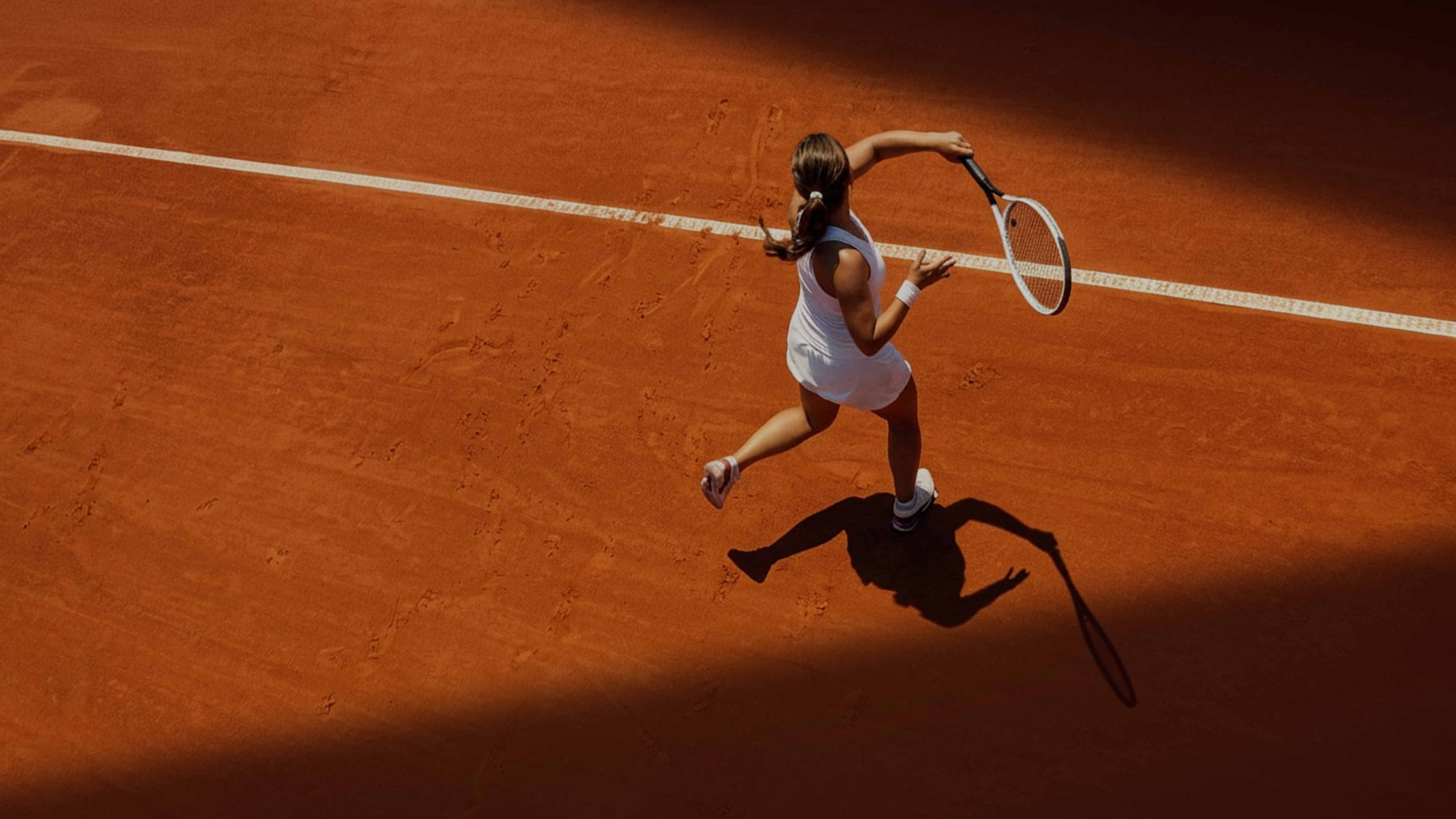 Woman playing tennis on a clay tennis court.