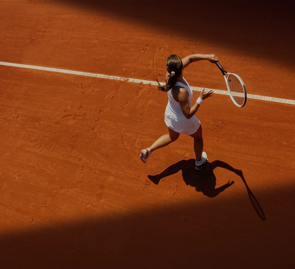 Woman playing tennis on a clay tennis court.