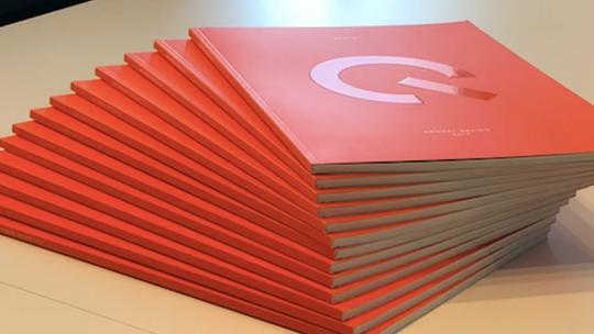 A stack of red books with a large white letter "G" on the cover, arranged neatly on a table.