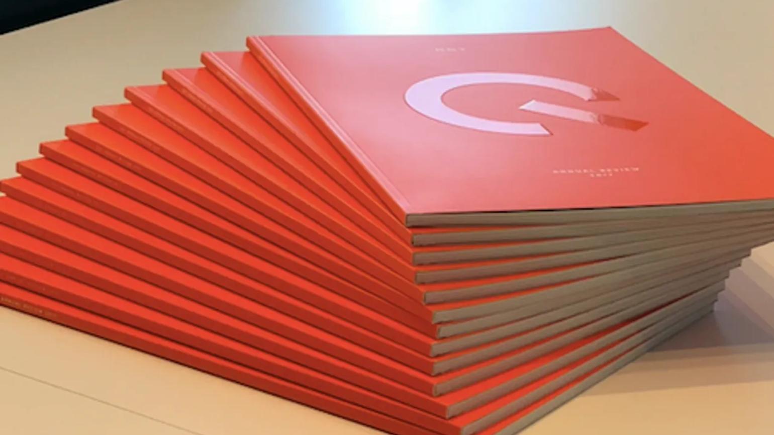 A stack of red books with a large white letter "G" on the cover, arranged neatly on a table.