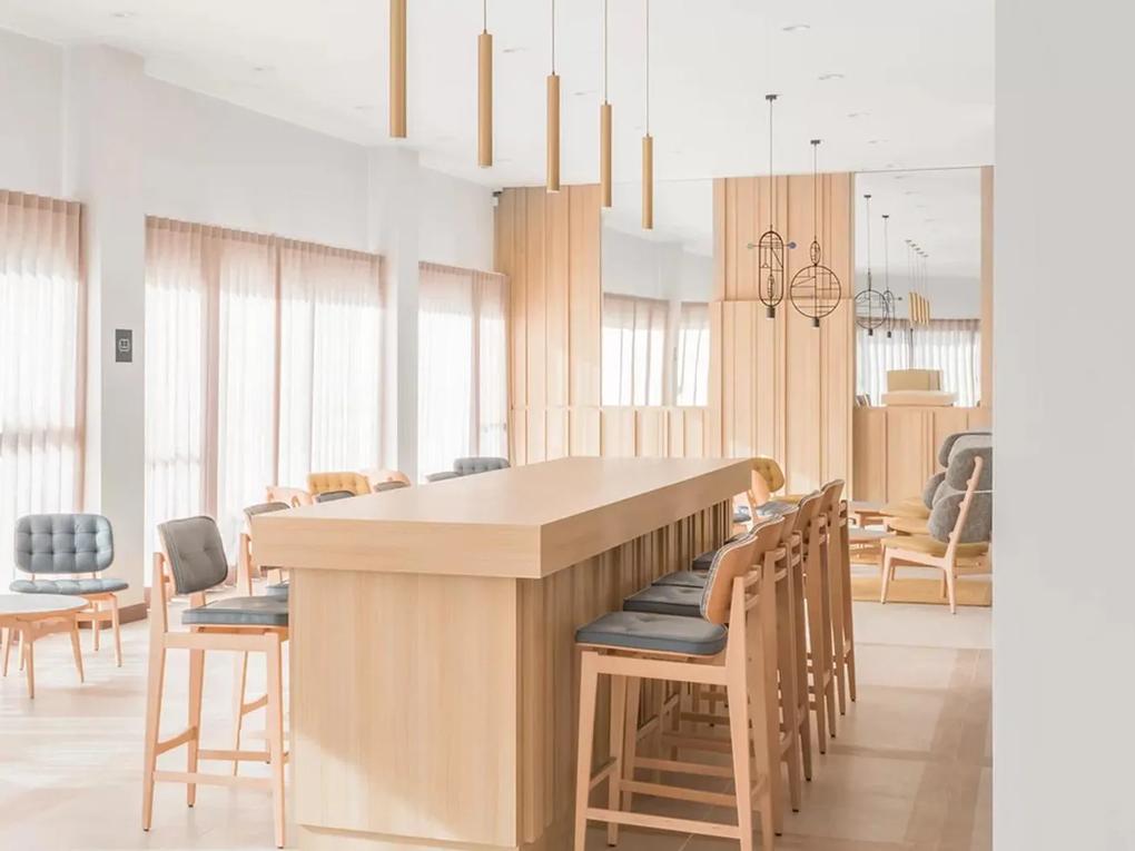 A modern, minimalist dining area with a long wooden table surrounded by high chairs.