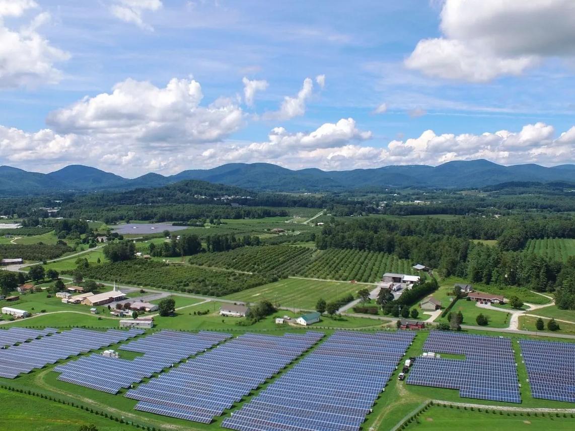 Aerial view of a solar farm with rows of solar panels in a rural landscape.
