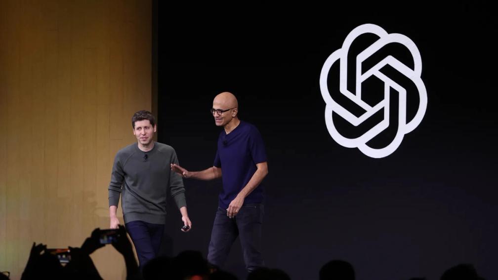 Sam Altman, CEO of OpenAI, and Satya Nadella, CEO of Microsoft, standing side-by-side on a stage in San Francisco 