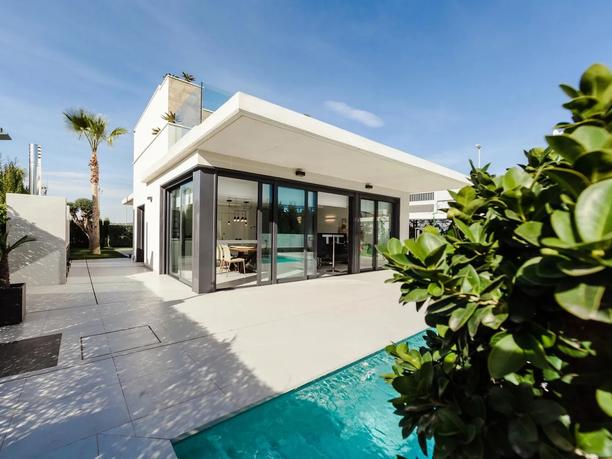 A modern, single-story house with large glass doors opening to a patio.