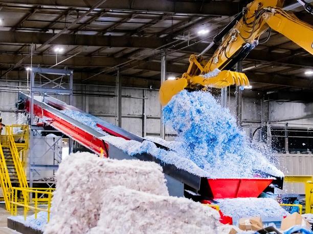 A large industrial machine processing shredded blue and white material.