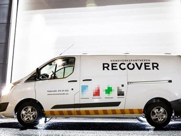 A white van parked in front of a brightly lit building.