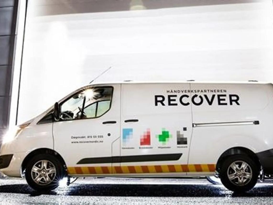 A white van parked in front of a brightly lit building.