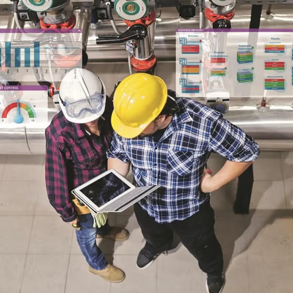 Two persons in helmets looking at a tablet.