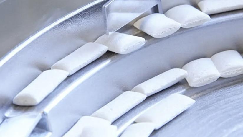 Close-up of white pieces on a metal conveyor belt.