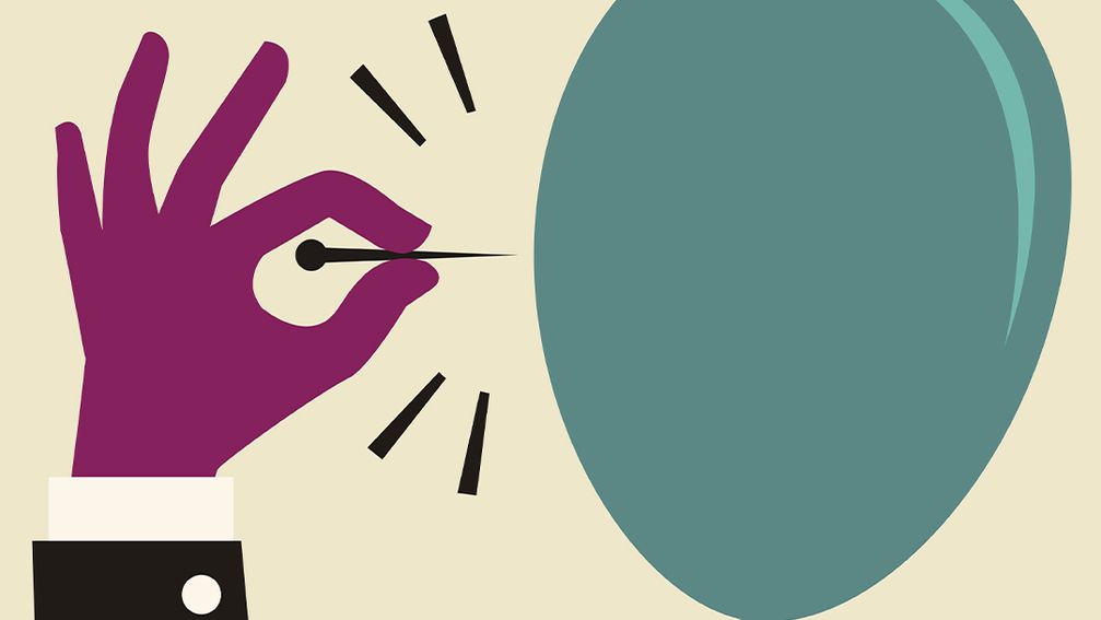 A hand holds a pin that's about to pop a balloon.