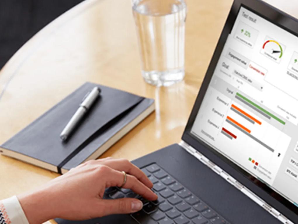A person using a laptop displaying a dashboard with graphs and metrics.