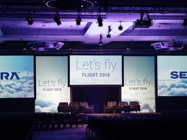 A conference stage with large screens displaying.