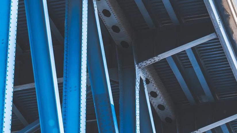 Close-up view of blue steel beams and rivets forming part of a bridge structure.