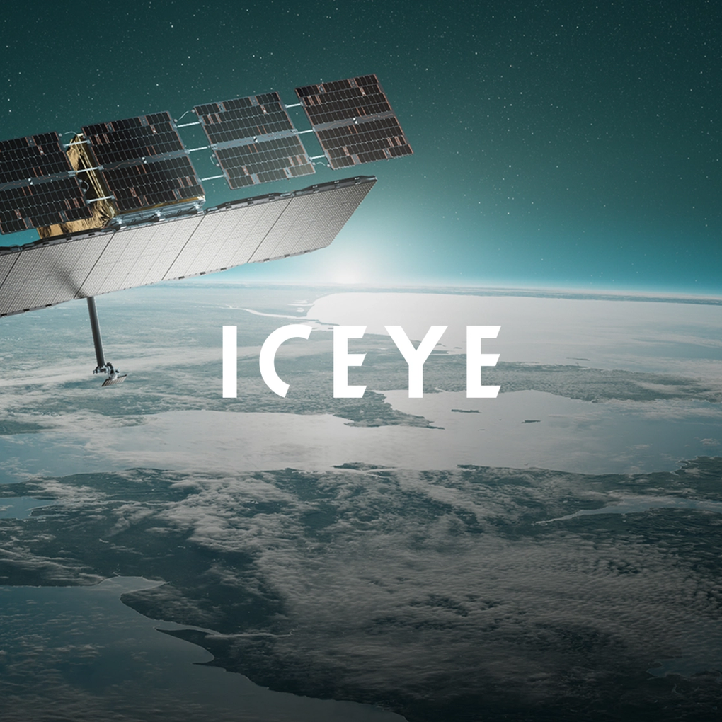 A satelite floating in space with the earth in the background, and with the logo "ICEYE".