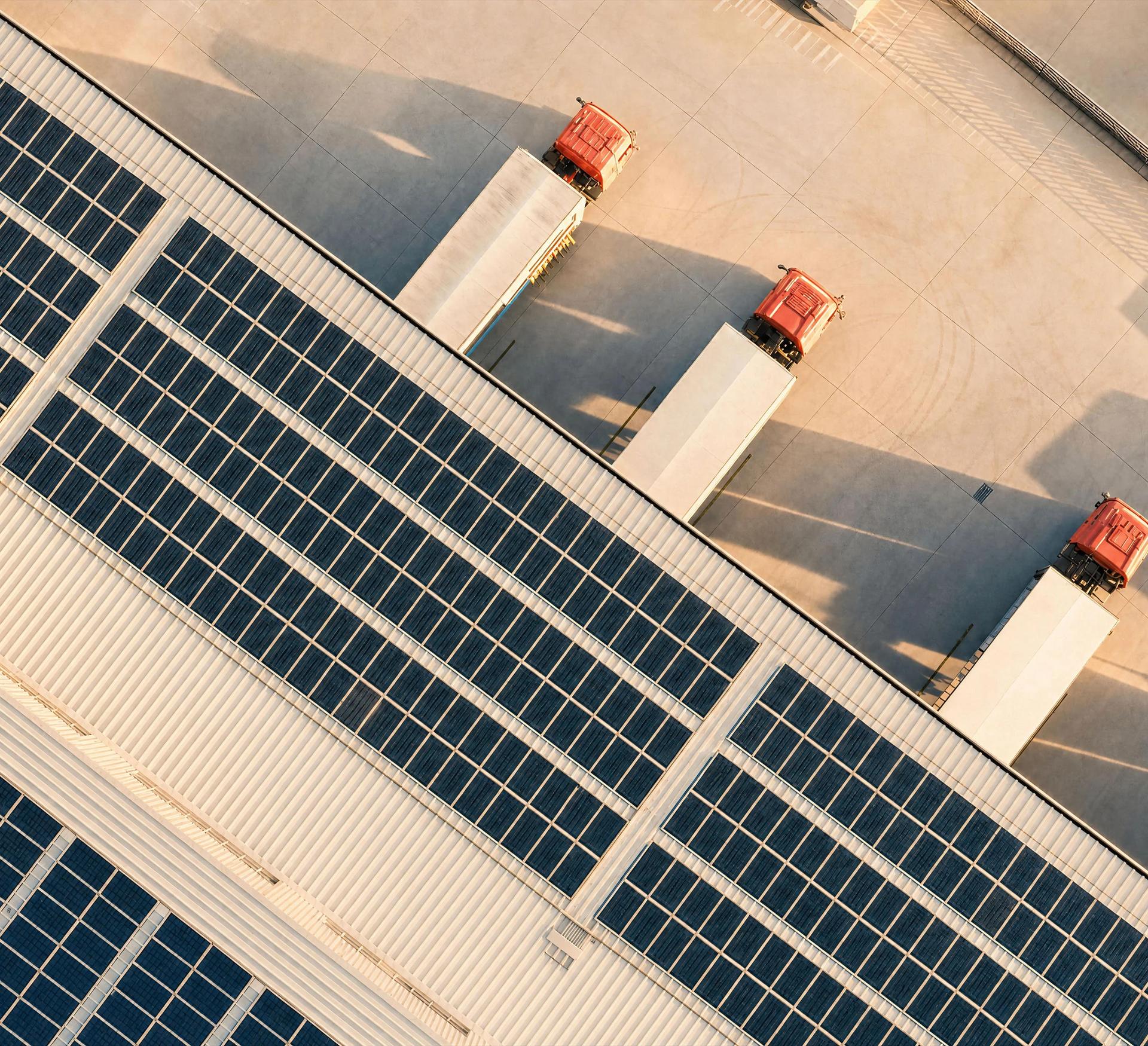 Warehouse with solar panels on the roof and three trucks.