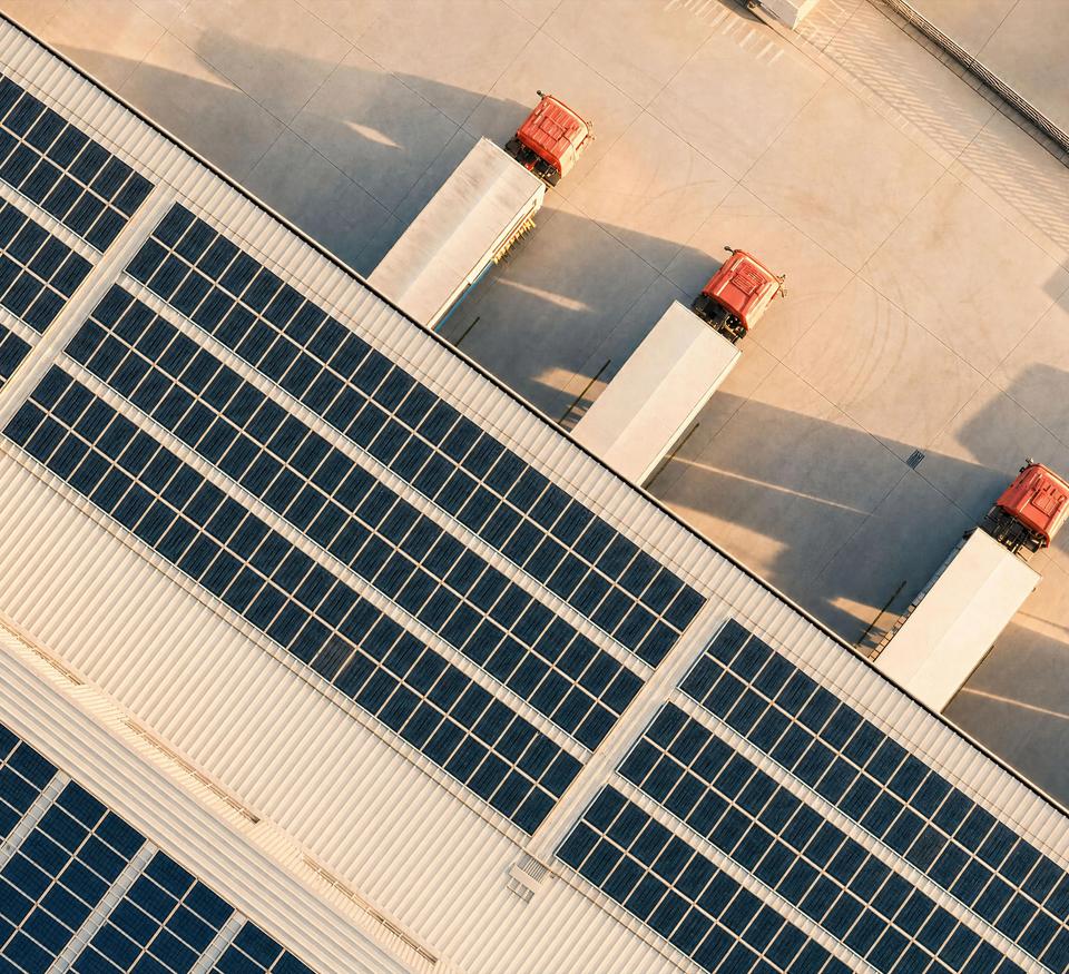 Warehouse with solar panels on the roof and three trucks.