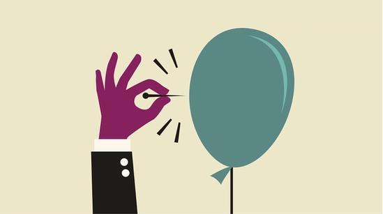 A hand holds a pin that's about to pop a balloon.