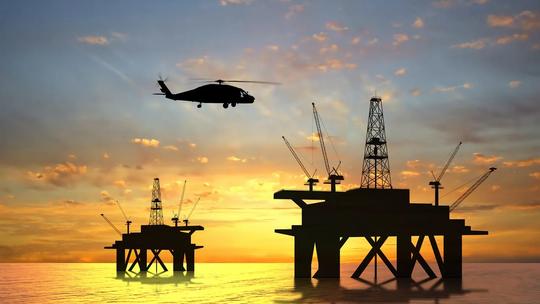 A helicopter flying over offshore oil platforms at sunset, with silhouettes of cranes and structures against a colorful sky.