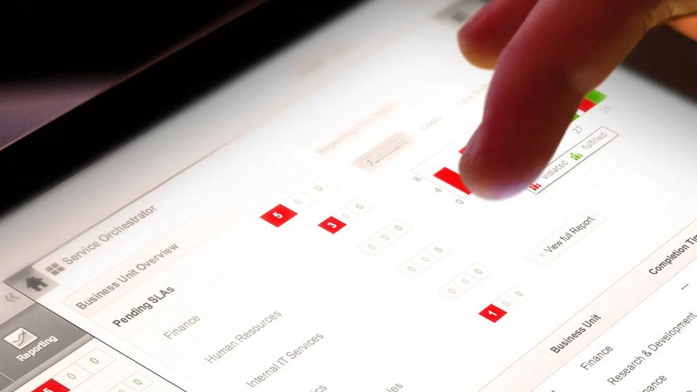 A close-up of a finger interacting with a digital dashboard on a tablet, displaying business unit performance metrics and service level agreements.