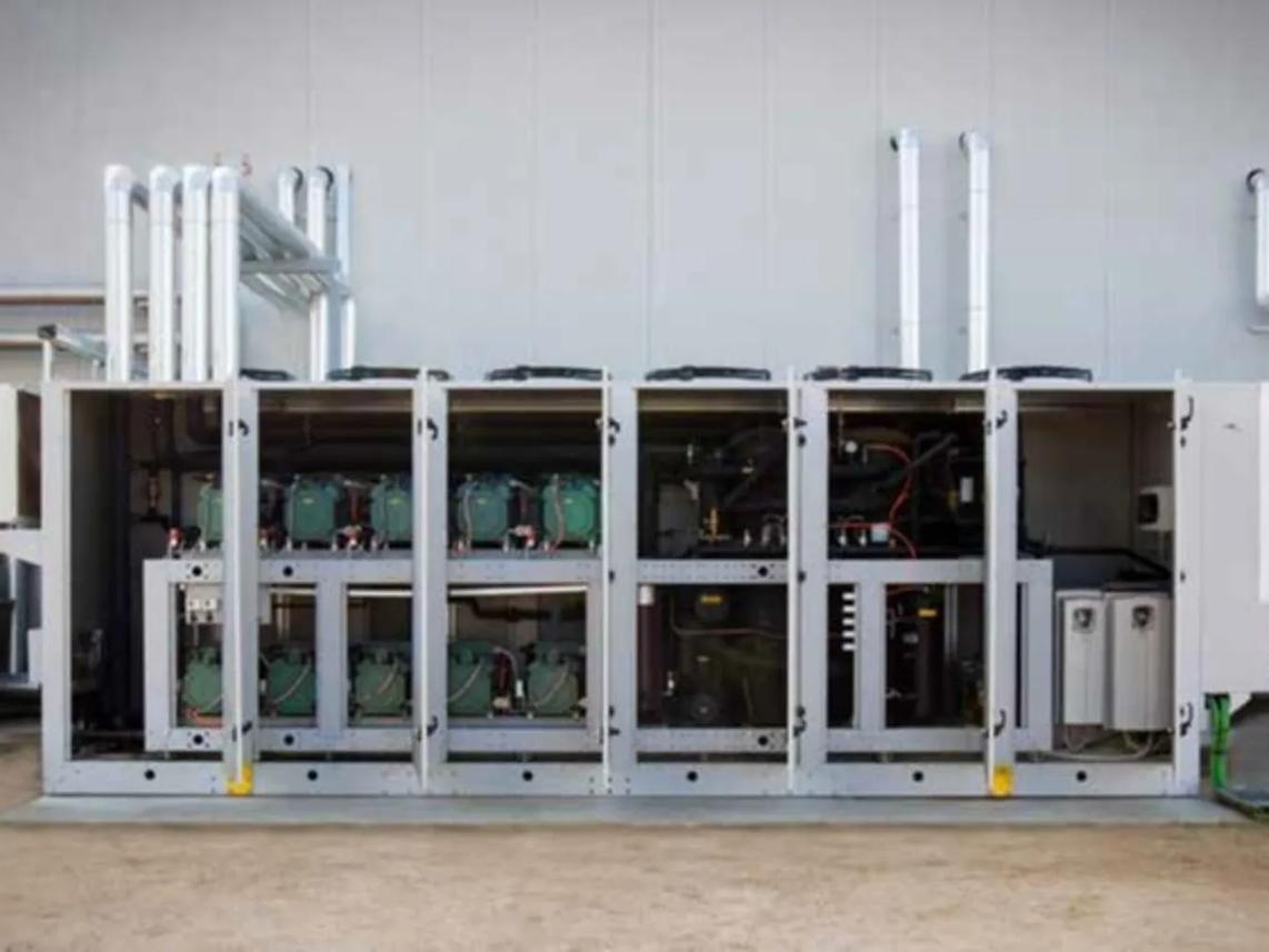 An industrial refrigeration unit with multiple compartments and visible piping, set against a plain wall.