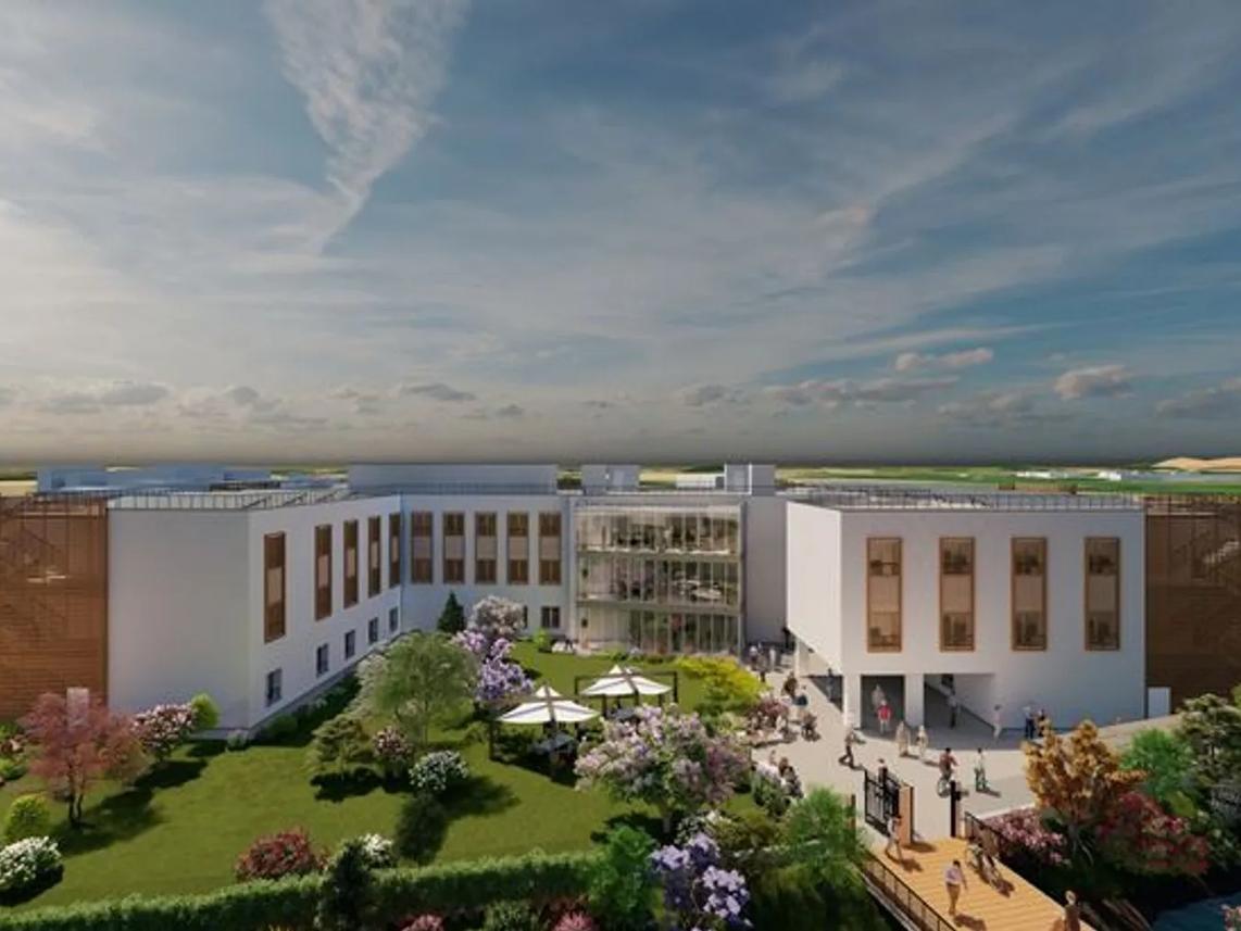 A modern building with a central glass atrium, surrounded by landscaped gardens and pathways.