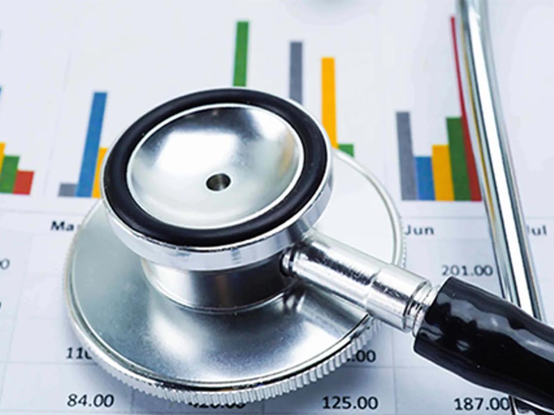 A stethoscope resting on a financial chart with colorful bar graphs.