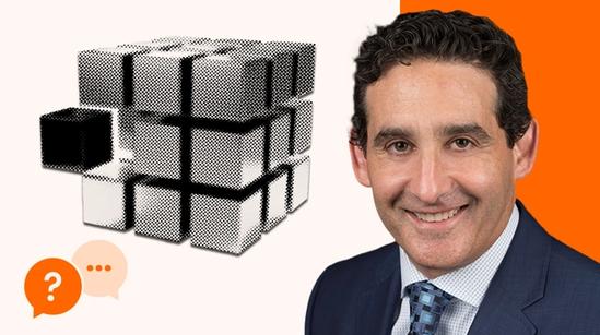Halftone illustration of a cube with one block pulled out, next to a portrait of a smiling man in a suit, with two speech‑bubble icons in the corner.