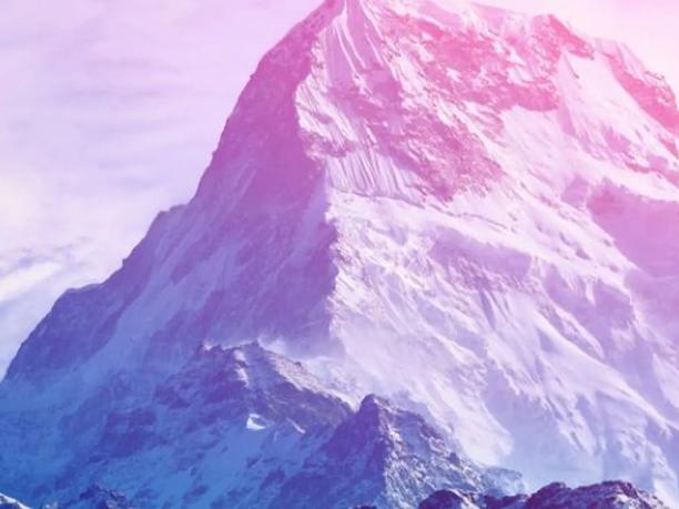 A snow-covered mountain peak under a pink and purple sky.
