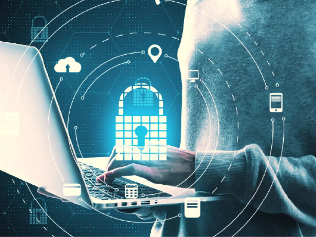 A person using a laptop with digital security icons, including a lock, cloud, and location symbol, overlaying the image, representing cybersecurity.