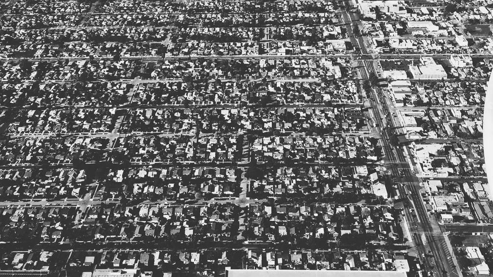 Aerial black and white view of a densely packed urban neighborhood.