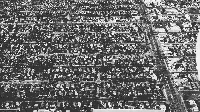 Aerial black and white view of a densely packed urban neighborhood.