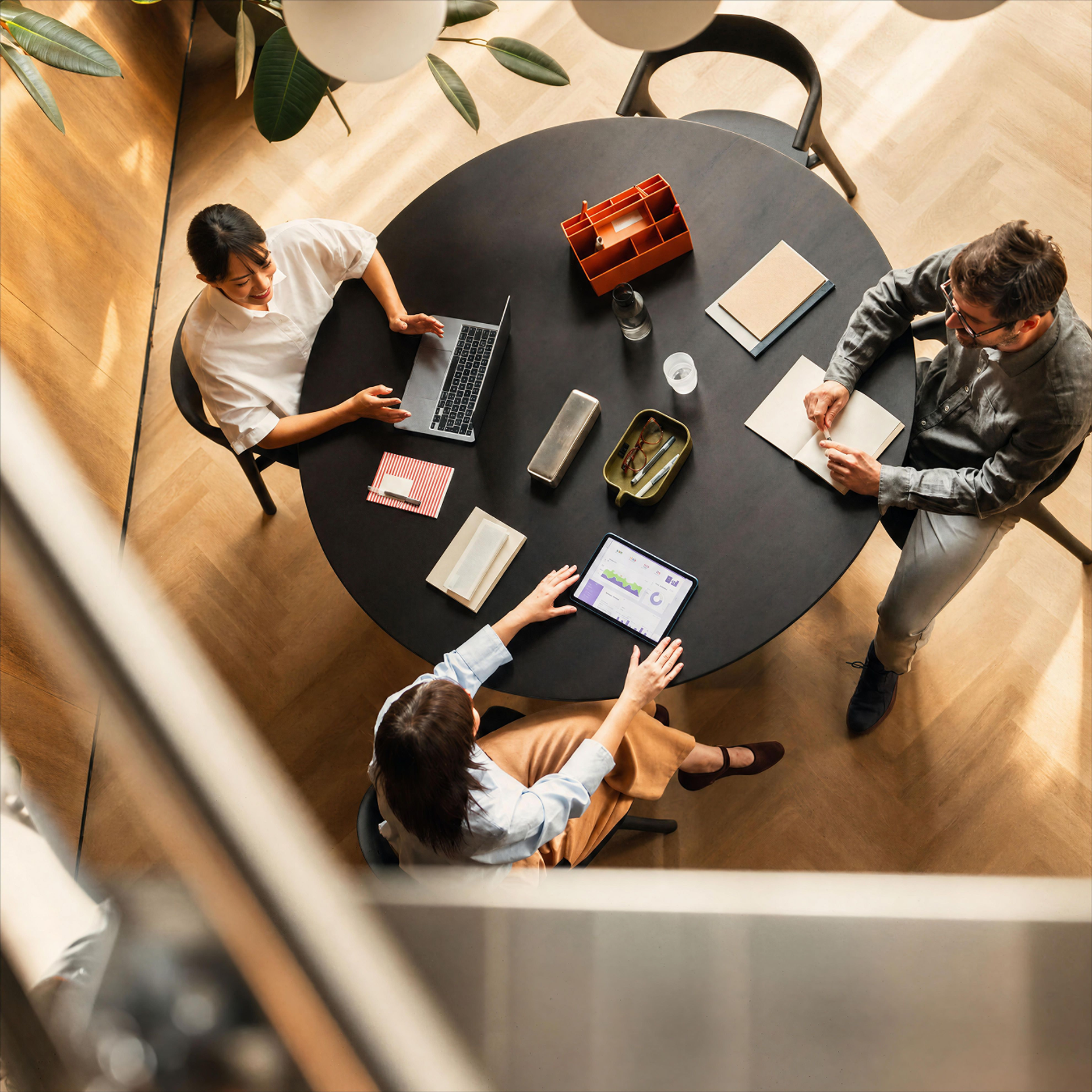 Three people working around a round table