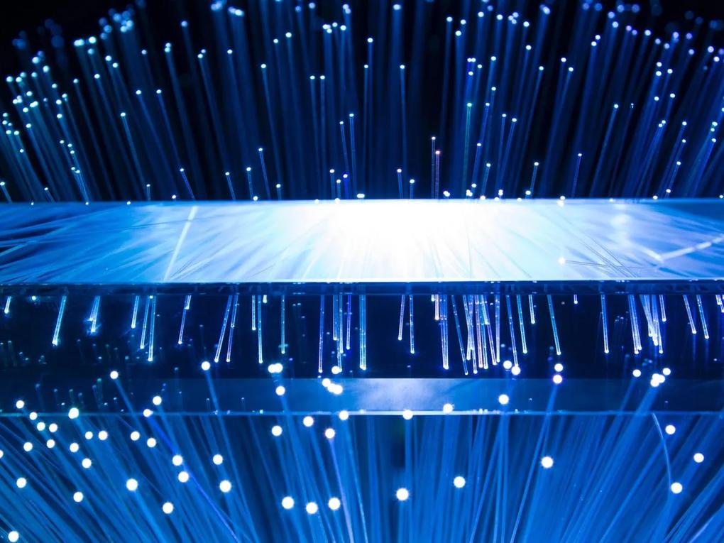 A close-up of blue fiber optic cables with glowing tips, creating a dynamic and futuristic visual effect.