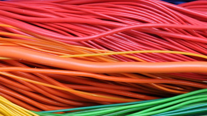 Close-up of colorful electrical wires, including red, orange, yellow, green, and blue, intertwined together.