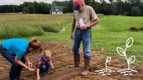 A multigenerational American family plants seeds in the ground.