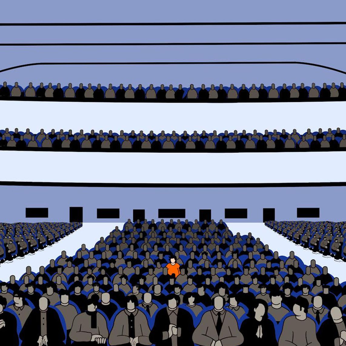 A figure in an orange shirt sits among many figures wearing dark clothes.