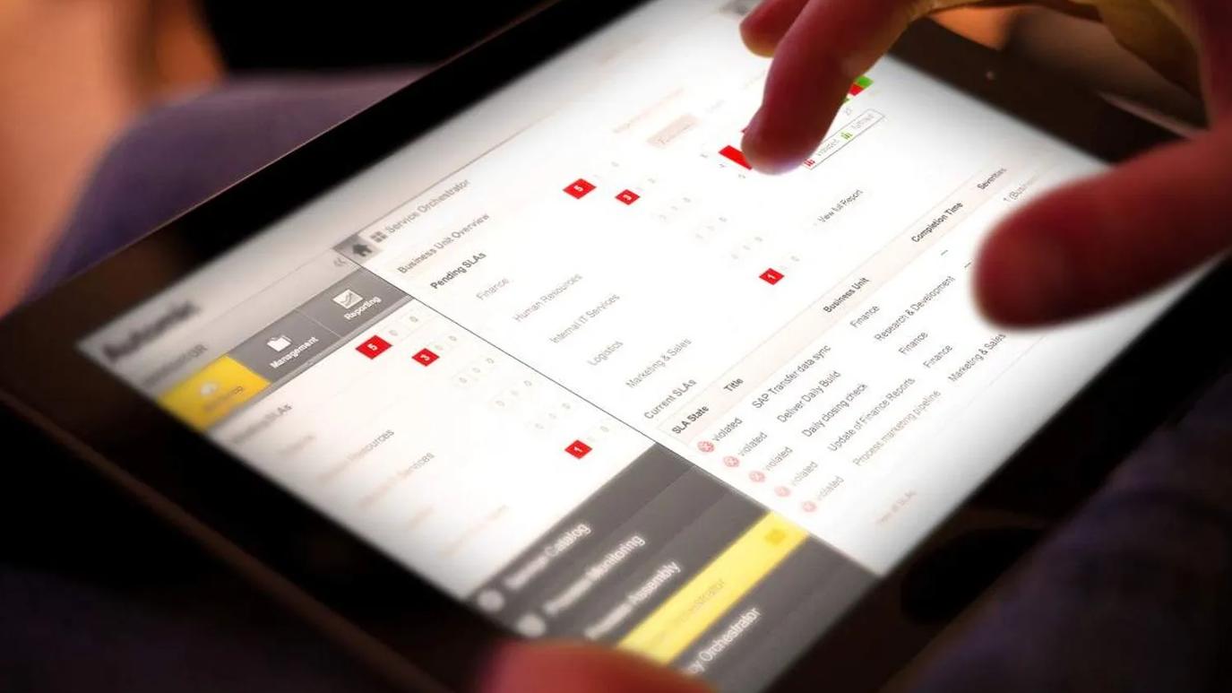 A person interacting with a tablet displaying a business dashboard interface, featuring various data metrics and reporting options.
