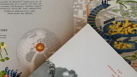 A close-up of the EQT Annual Review 2014 booklet, featuring illustrations of global business concepts, including a globe and diagrams depicting growth and sustainability strategies.